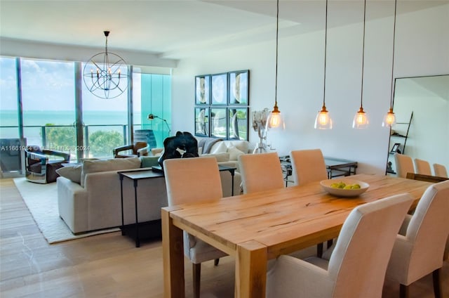 dining area with an inviting chandelier, light wood-type flooring, and a water view