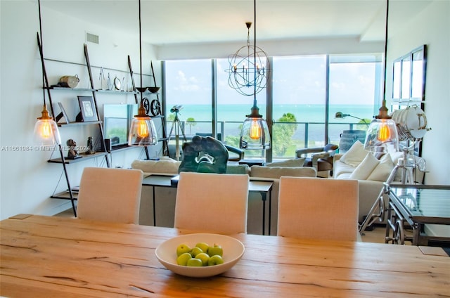 dining space with plenty of natural light, a chandelier, and a water view