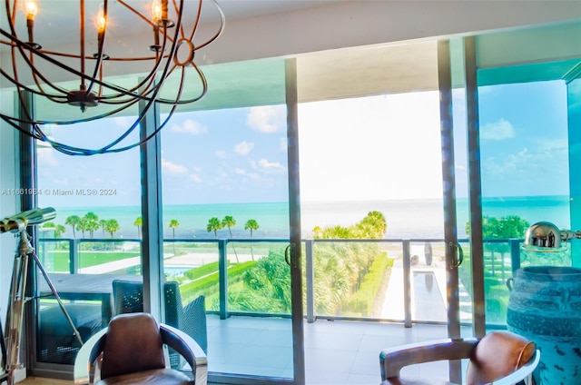 workout area featuring a healthy amount of sunlight, a water view, and a notable chandelier