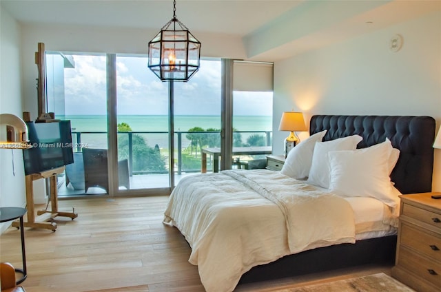 bedroom featuring access to outside, an inviting chandelier, a wall of windows, and light hardwood / wood-style floors