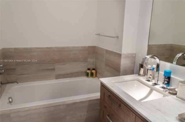 bathroom featuring tiled tub and vanity