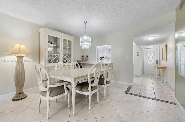 tiled dining space with a notable chandelier and a textured ceiling