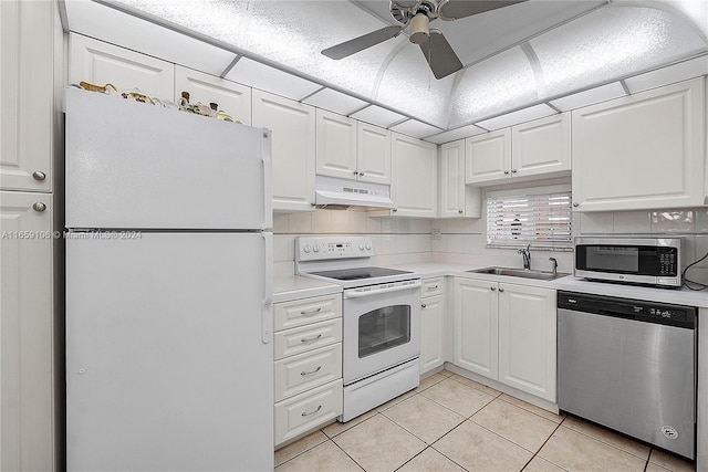 kitchen with appliances with stainless steel finishes, light tile patterned flooring, white cabinetry, ceiling fan, and sink