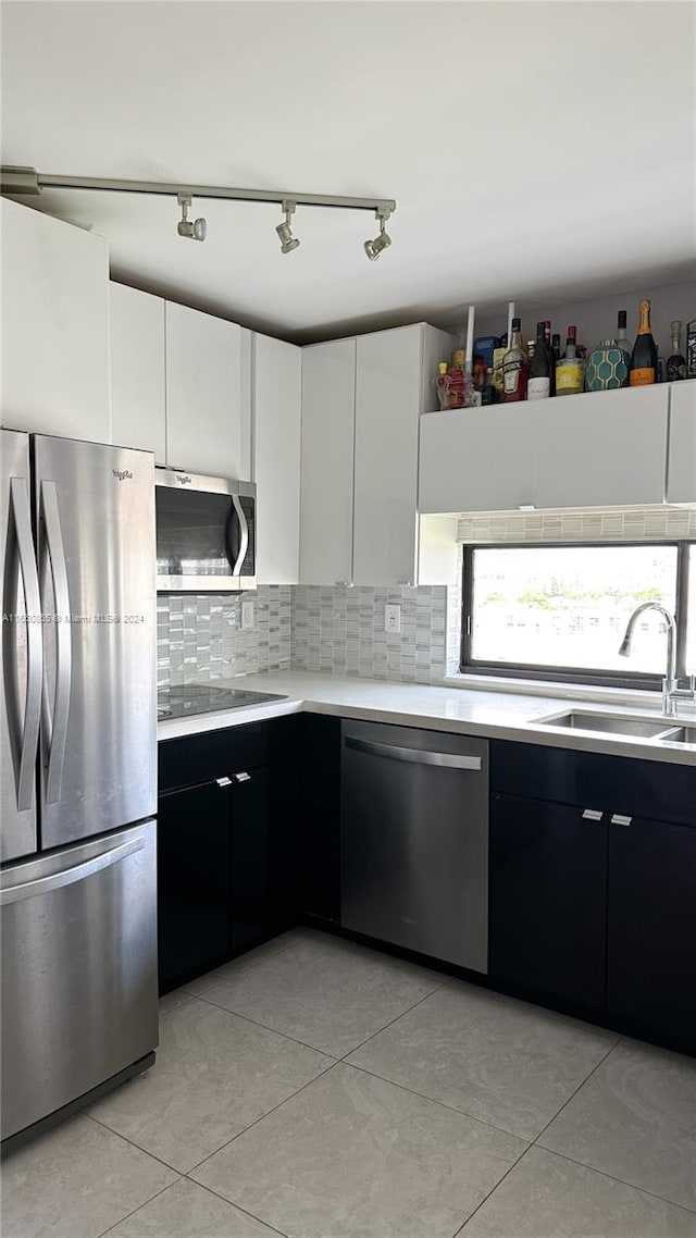 kitchen with white cabinetry, appliances with stainless steel finishes, light tile patterned floors, and sink