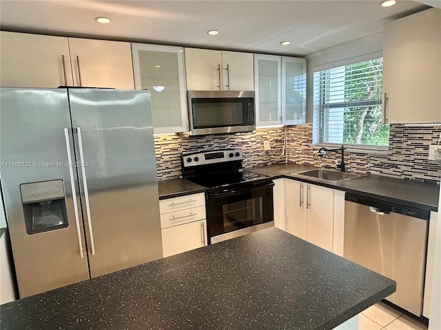 kitchen with white cabinets, light tile patterned floors, sink, tasteful backsplash, and appliances with stainless steel finishes