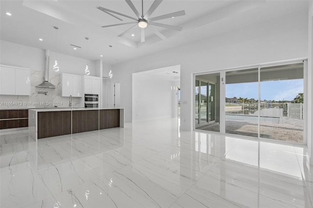 kitchen with white cabinetry, dark brown cabinetry, range hood, ceiling fan, and a center island with sink