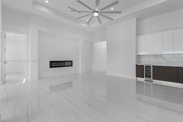 unfurnished living room featuring heating unit, a tray ceiling, and ceiling fan