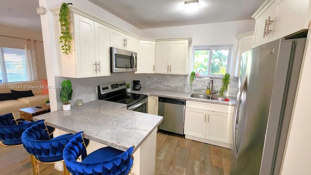 kitchen featuring a breakfast bar, light wood-type flooring, sink, kitchen peninsula, and stainless steel appliances