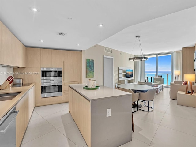 kitchen with a kitchen island, decorative light fixtures, stainless steel appliances, light brown cabinetry, and a breakfast bar area