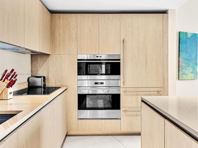 kitchen featuring stainless steel double oven, black electric stovetop, light brown cabinets, and light tile patterned floors