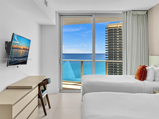 bedroom with multiple windows, a water view, light tile patterned flooring, and access to exterior