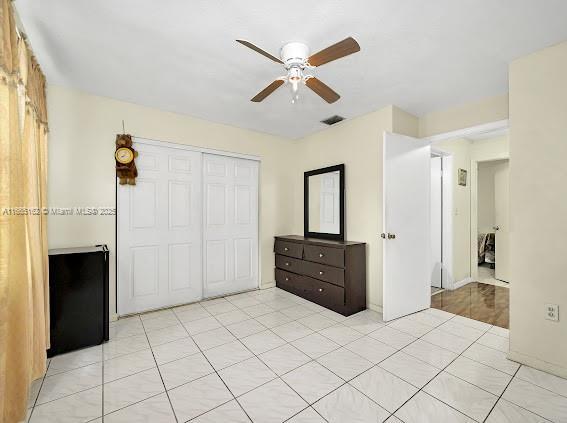 unfurnished bedroom featuring light tile patterned floors, ceiling fan, visible vents, and a closet