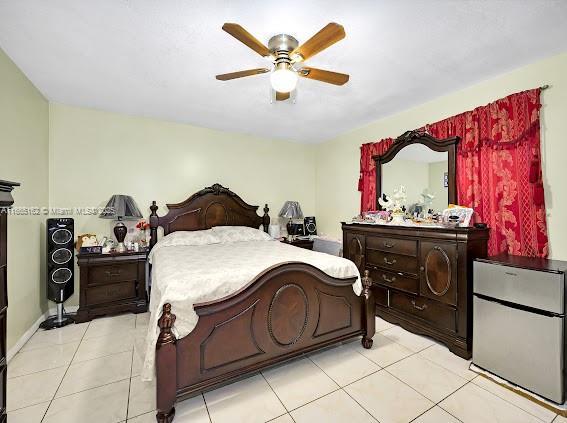 bedroom with fridge, ceiling fan, and light tile patterned floors