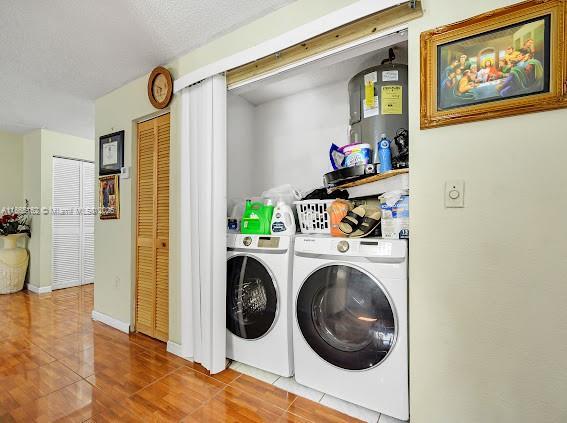 laundry room with independent washer and dryer, tile patterned floors, and a textured ceiling