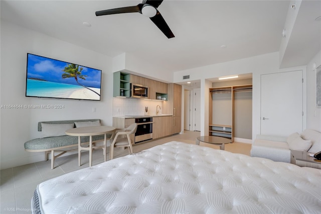 bedroom with ceiling fan, sink, light tile patterned floors, a walk in closet, and a closet