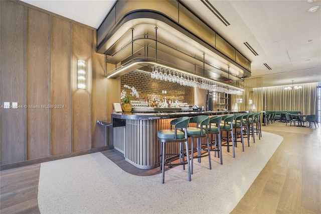 bar with wood-type flooring, wood walls, and a chandelier