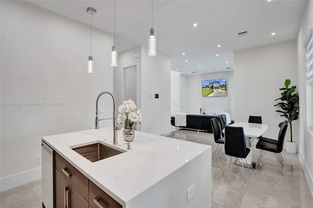 kitchen featuring hanging light fixtures, a center island with sink, dishwasher, and sink