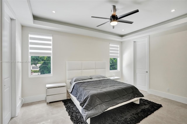 bedroom featuring a tray ceiling, multiple windows, and ceiling fan