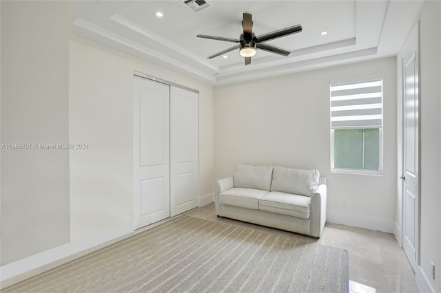 living area with a tray ceiling and ceiling fan