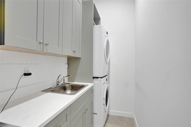 laundry area featuring cabinets, stacked washer / dryer, and sink