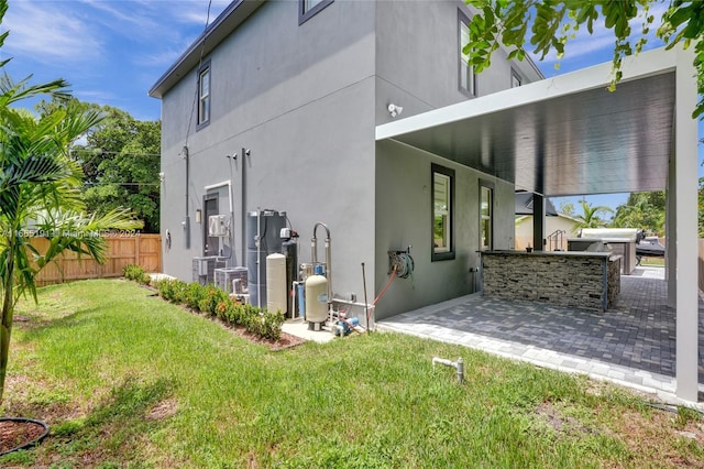 rear view of house with a patio, a yard, central AC unit, and an outdoor kitchen