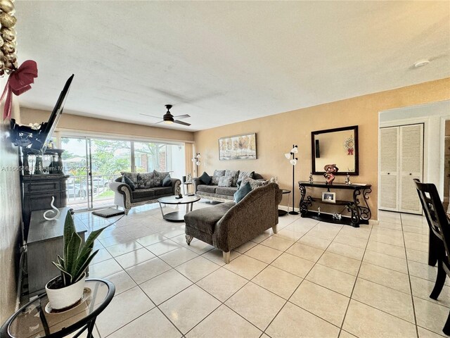 living room featuring light tile patterned flooring and ceiling fan with notable chandelier