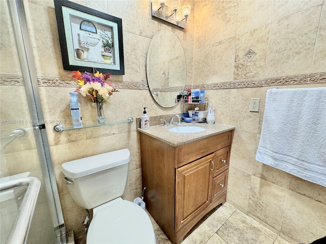 bathroom featuring vanity, tile walls, and toilet