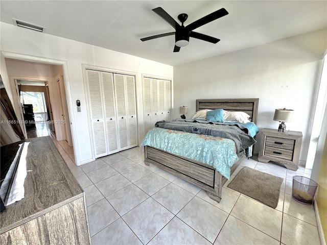 bedroom featuring ceiling fan, multiple closets, and light tile patterned flooring