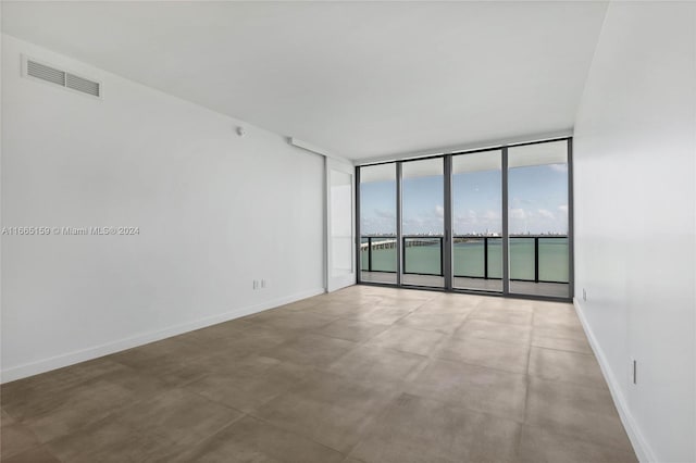 empty room featuring concrete floors, a water view, and expansive windows