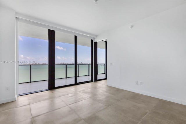 spare room with a wall of windows and a water view