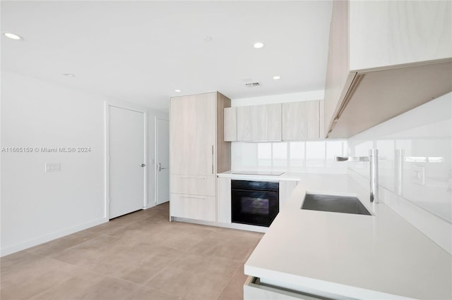 kitchen with black appliances, light brown cabinetry, sink, and light tile patterned floors