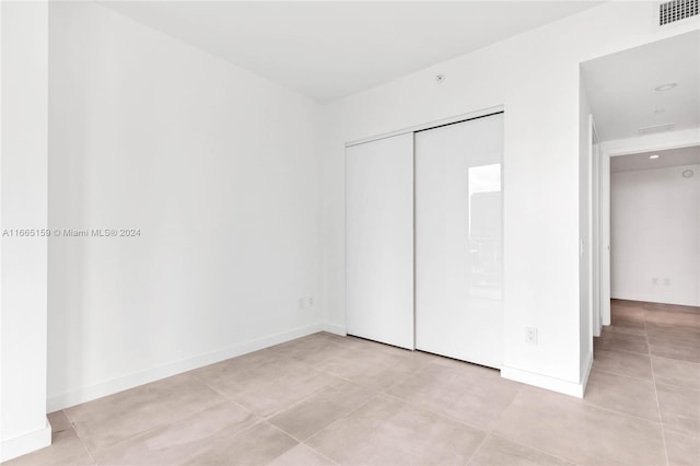 unfurnished bedroom featuring light tile patterned flooring and a closet