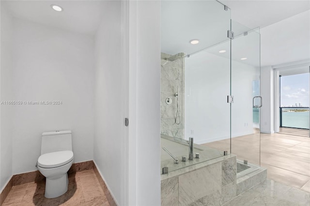 bathroom featuring a shower with shower door and toilet