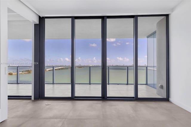 unfurnished room with a water view and expansive windows