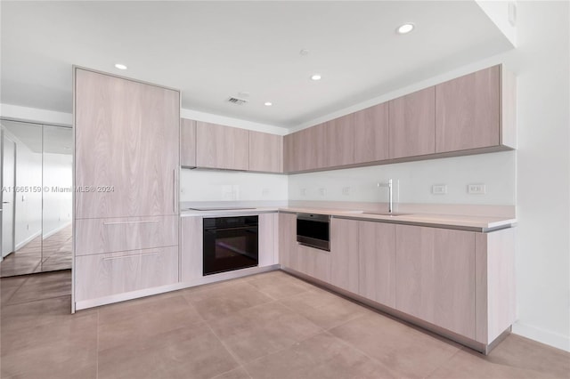 kitchen featuring black appliances, light brown cabinetry, and sink