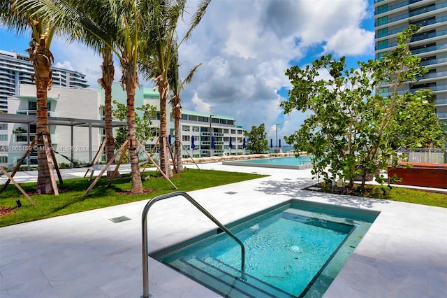 view of swimming pool with a yard and a hot tub