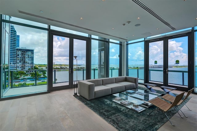 living room featuring hardwood / wood-style flooring, floor to ceiling windows, and a water view