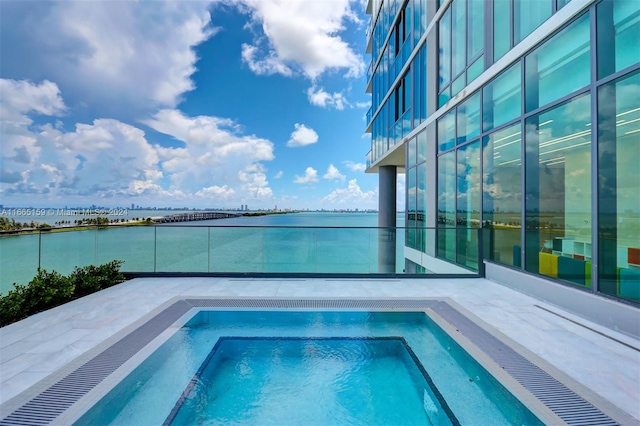 view of swimming pool with an in ground hot tub and a water view