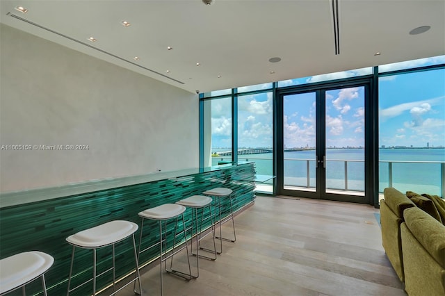 bathroom with floor to ceiling windows, a water view, and hardwood / wood-style flooring