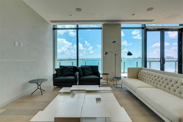 living room featuring a wall of windows, light wood-type flooring, and a water view