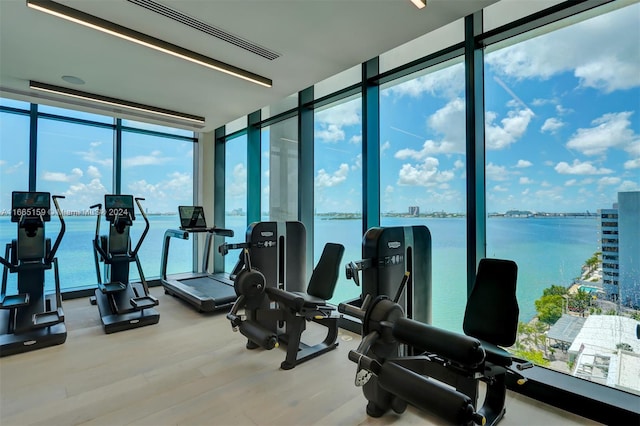 exercise room with a water view, floor to ceiling windows, and hardwood / wood-style flooring