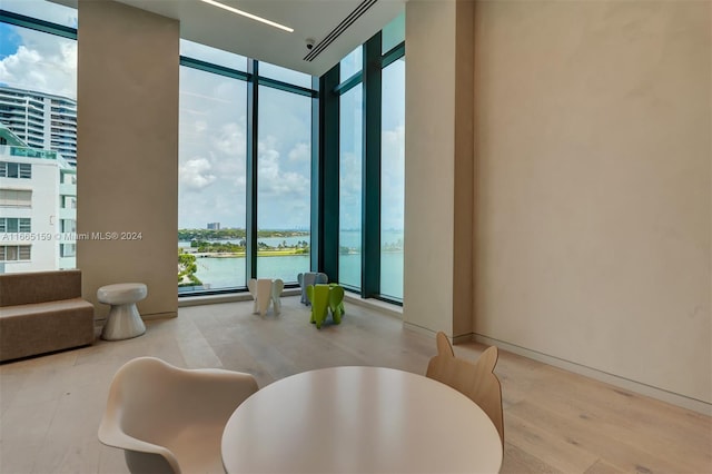 bathroom with hardwood / wood-style floors, a water view, and floor to ceiling windows