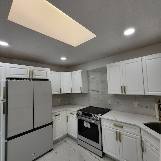 kitchen featuring appliances with stainless steel finishes, decorative backsplash, white cabinetry, and sink