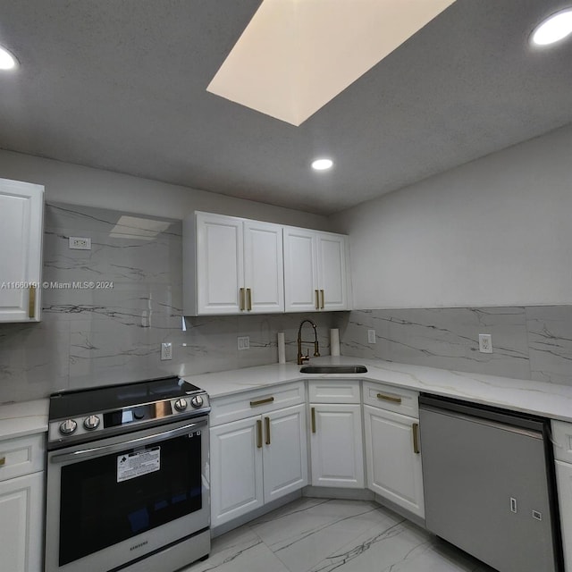 kitchen with appliances with stainless steel finishes, white cabinetry, and sink