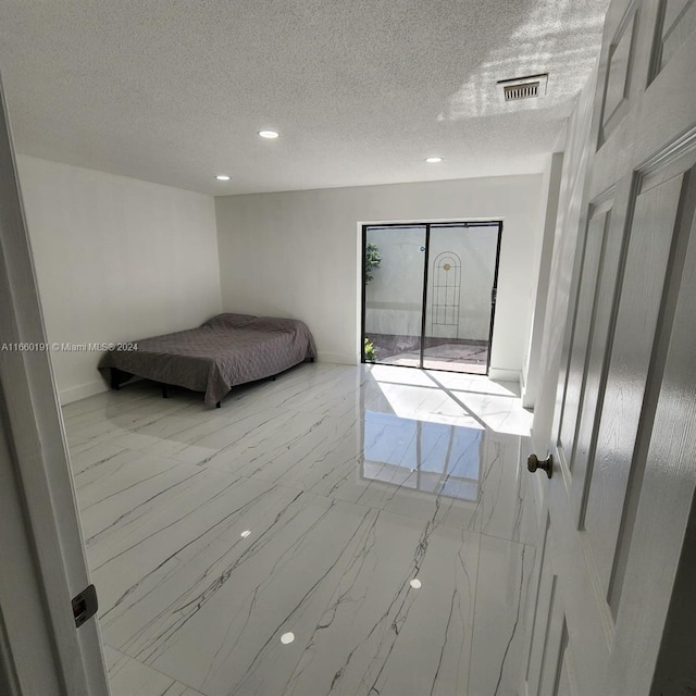 unfurnished bedroom featuring a textured ceiling and access to exterior