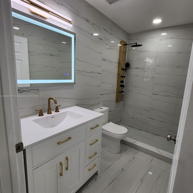 bathroom with tile walls, a tile shower, vanity, and toilet