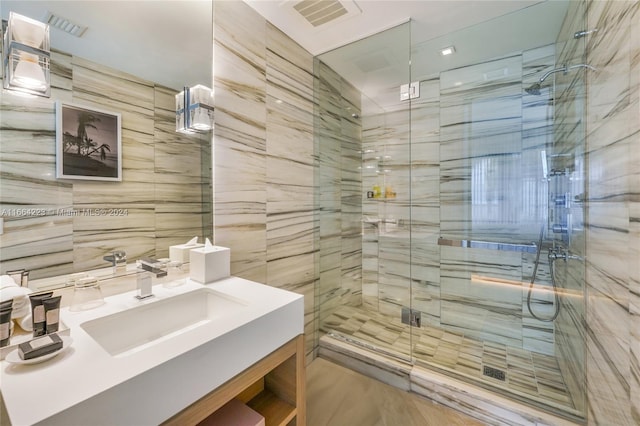 bathroom with tile walls, an enclosed shower, and vanity