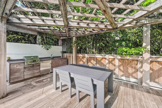 wooden deck featuring area for grilling, sink, a pergola, and exterior kitchen