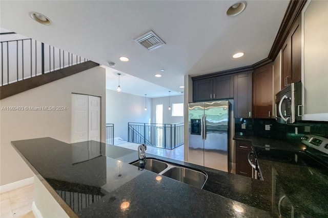 kitchen featuring sink, kitchen peninsula, appliances with stainless steel finishes, dark brown cabinetry, and dark stone countertops