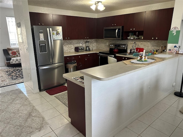 kitchen featuring decorative backsplash, stainless steel appliances, kitchen peninsula, and light tile patterned floors